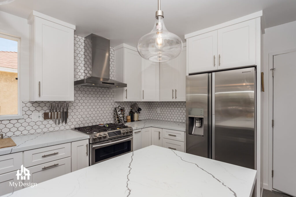 White kitchen with quartz island and pendant lights in a Hawthorn kitchen remodel