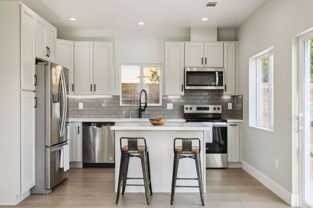 Two-bedroom ADU kitchen with a breakfast island, white cabinets and stainless appliances