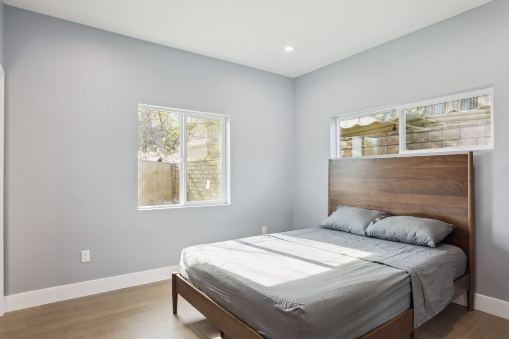 ADU bedroom with a wood headboard and twin windows
