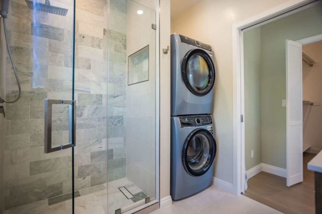 Stacked laundry beside the tiled shower in the Culver City two-storey ADU