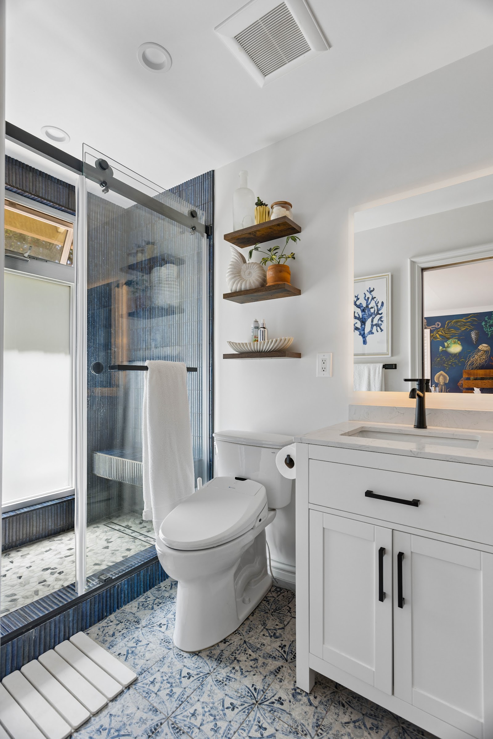 Bathroom remodel pairing blue tile with a white shaker vanity