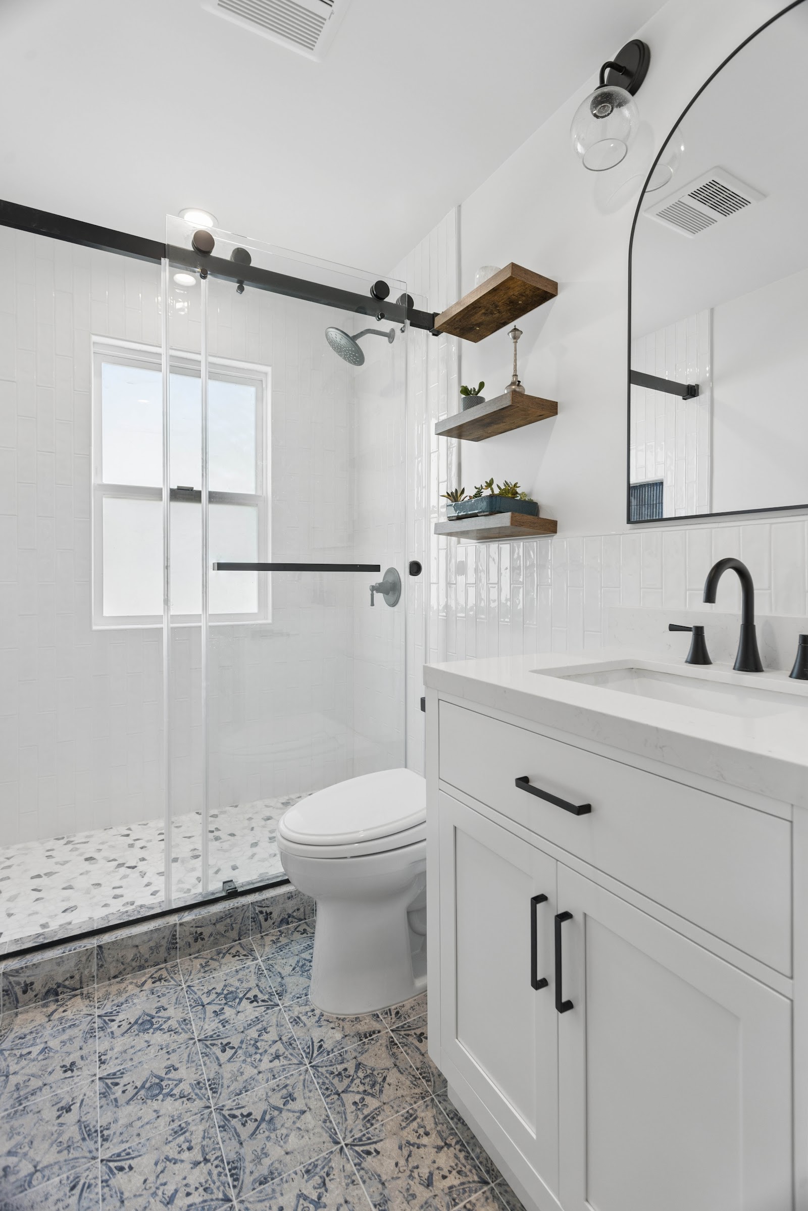 Bathroom with a sliding shower door, arched mirror and walnut shelving