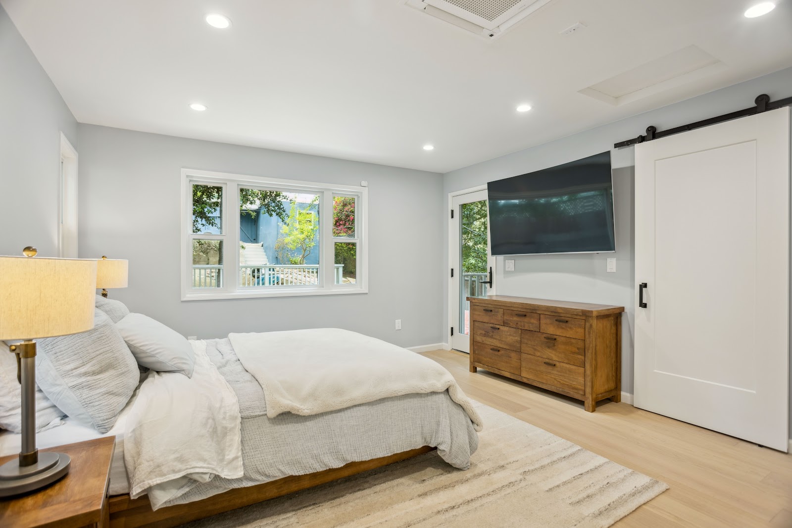 Bedroom remodel with a sliding barn door and light oak flooring