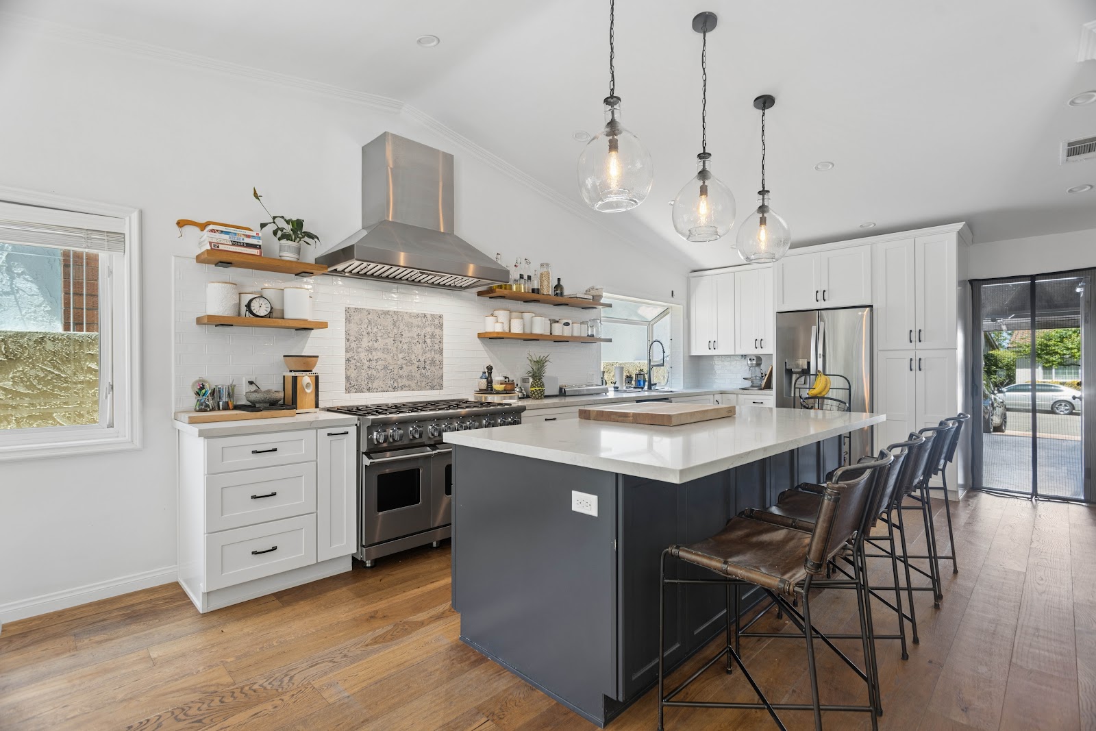 Charcoal island with leather bar stools under glass globe pendants