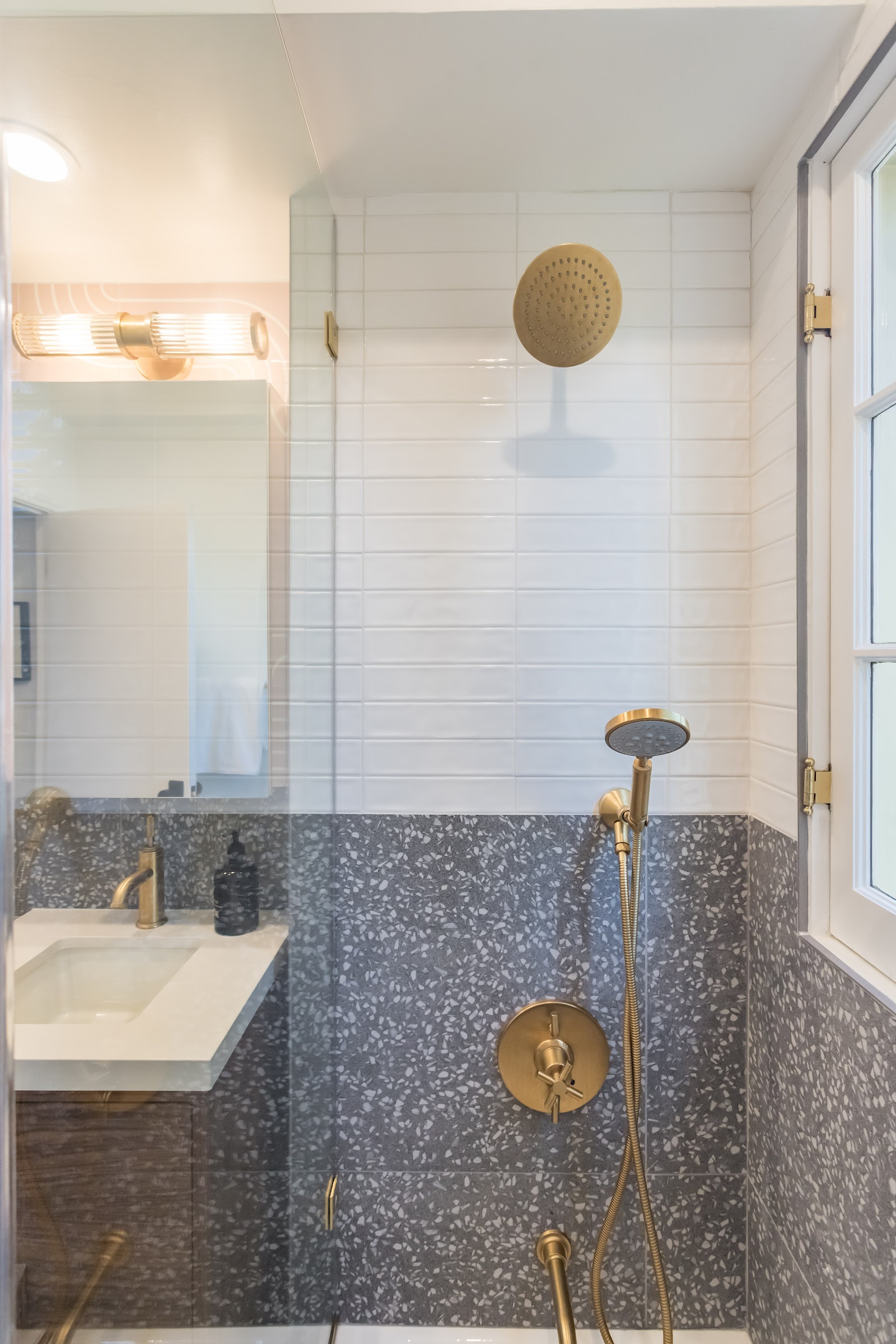 Compact bathroom with a brass shower set against grey terrazzo tile