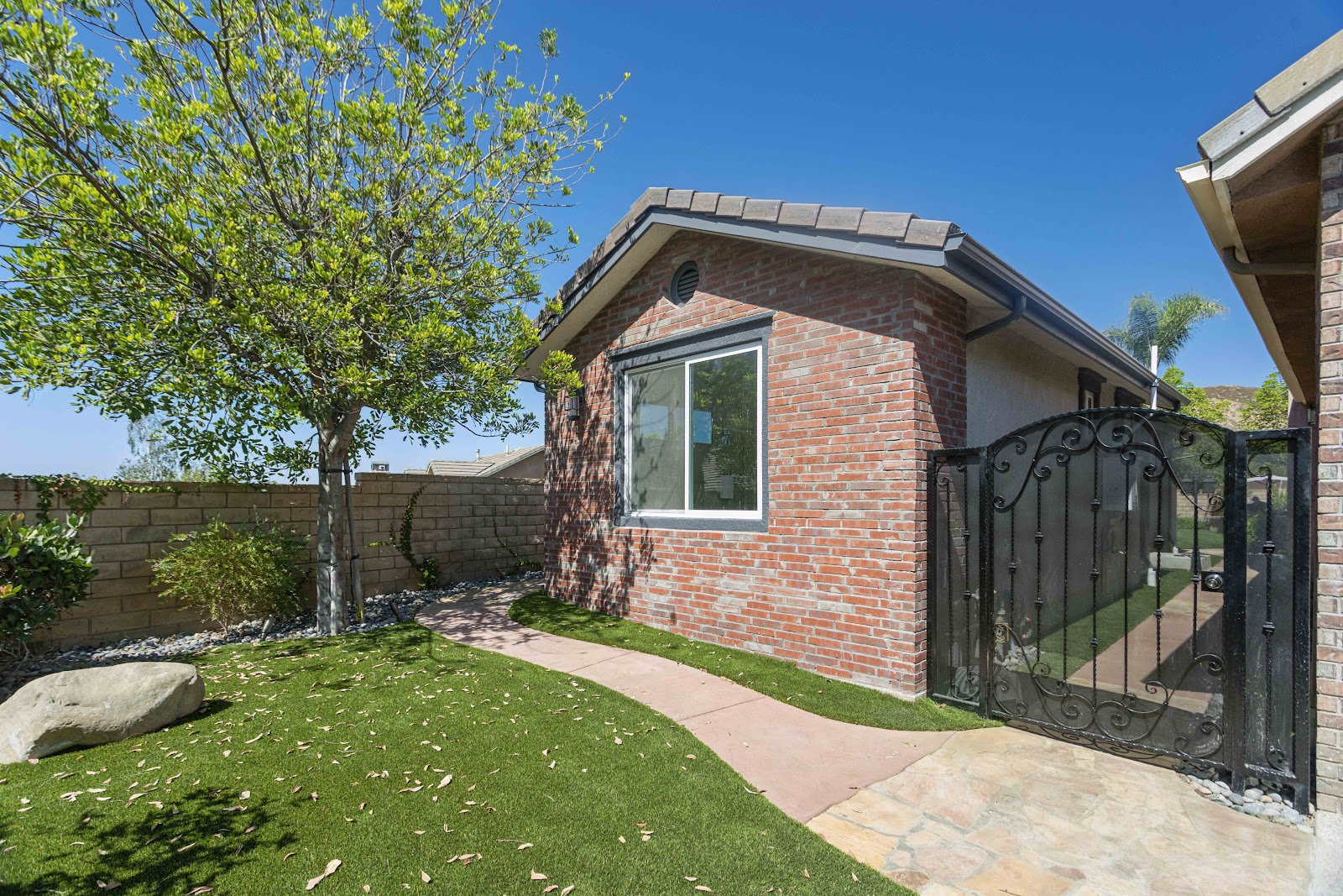 Detached backyard ADU in brick and stucco with a roof matching the main house