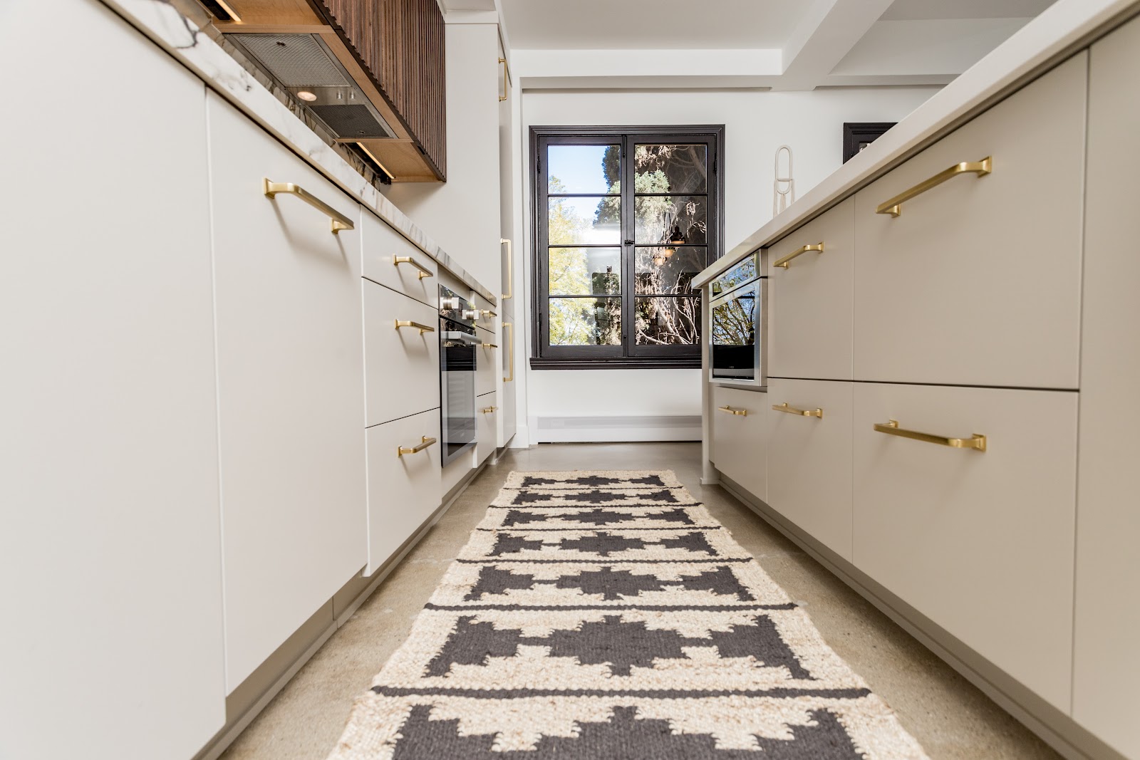 Galley pantry with cream cabinets, brass hardware and a patterned runner