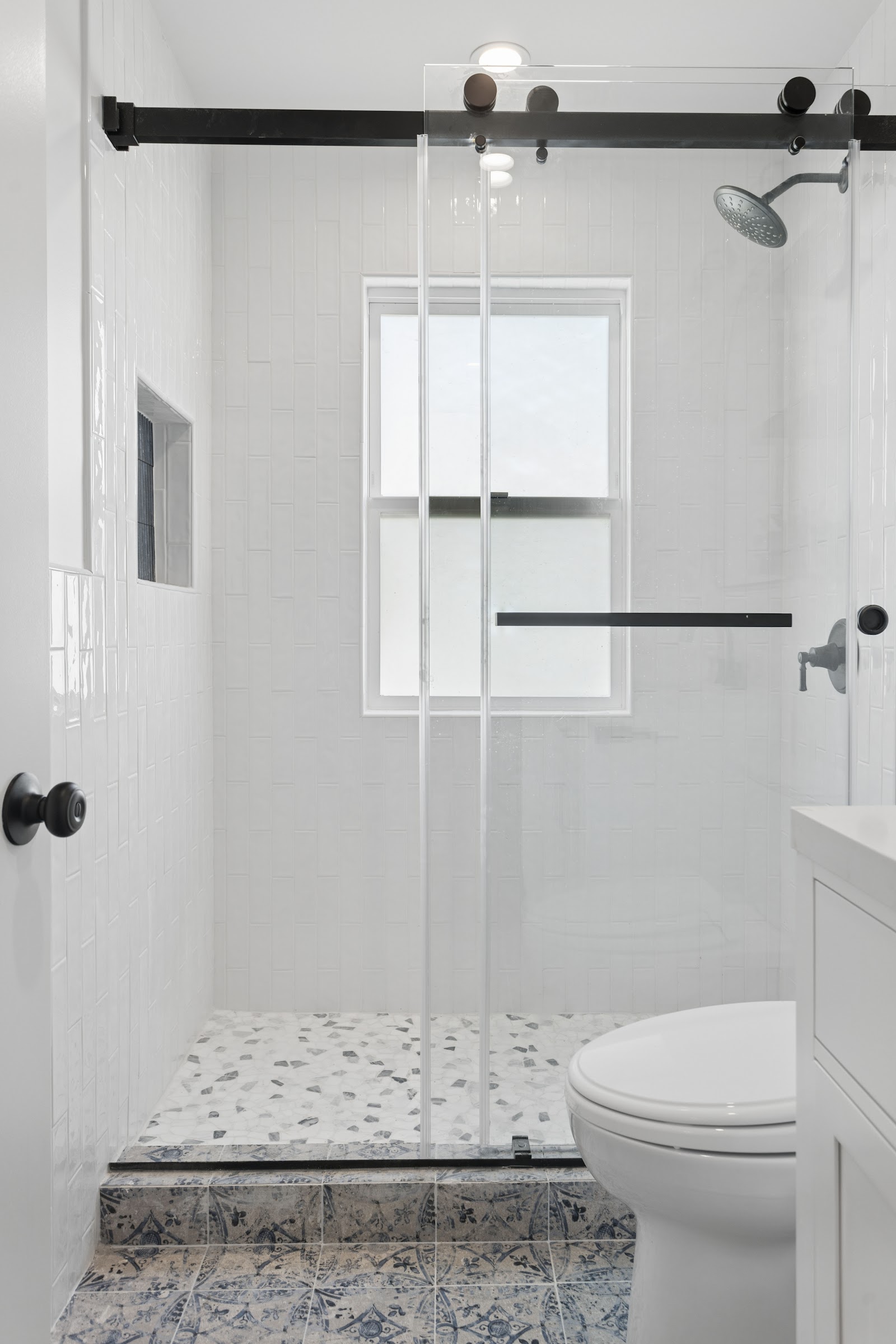 Guest bathroom with a mosaic shower floor and black sliding door hardware