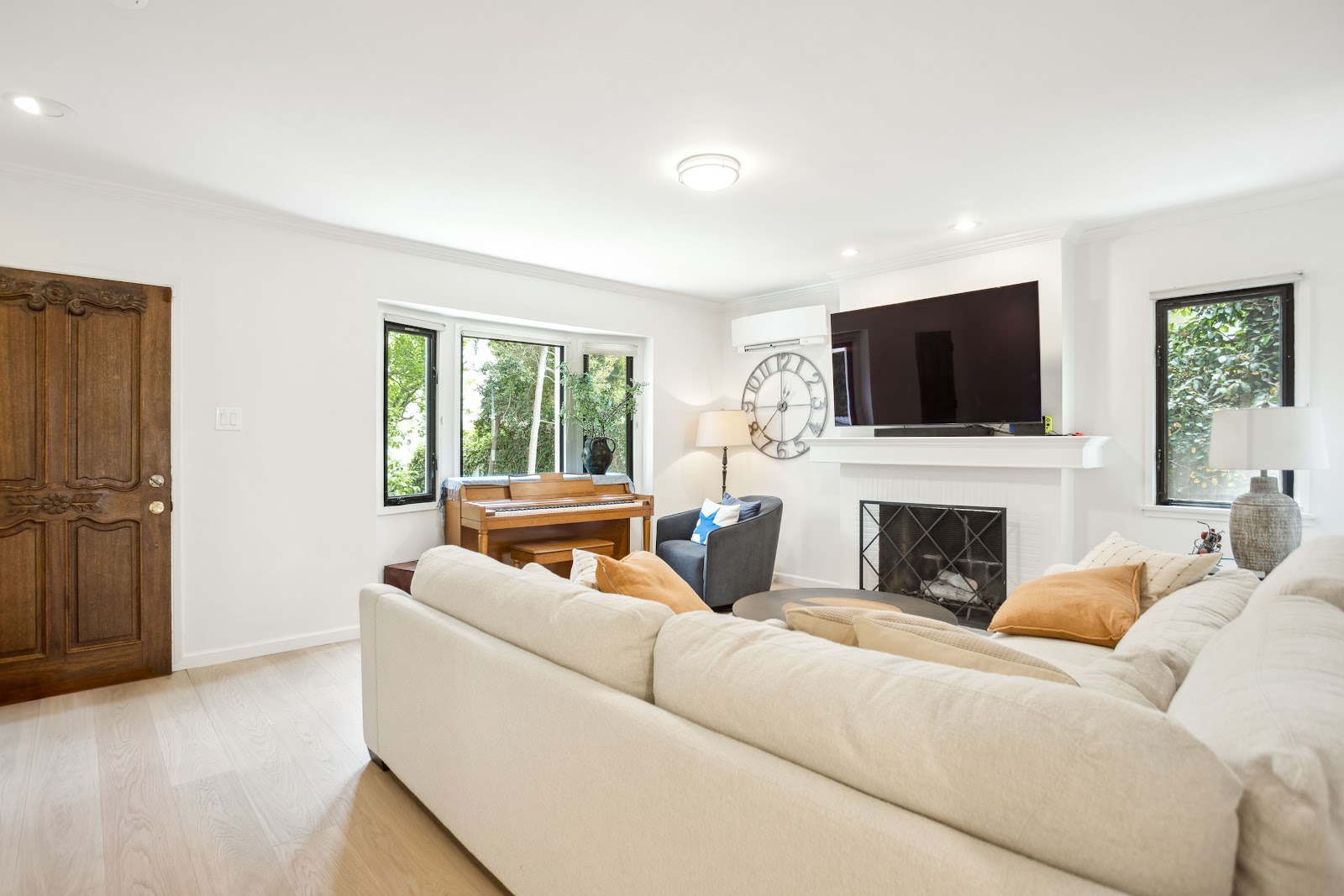 Living room with a fireplace, black steel windows and a wood front door