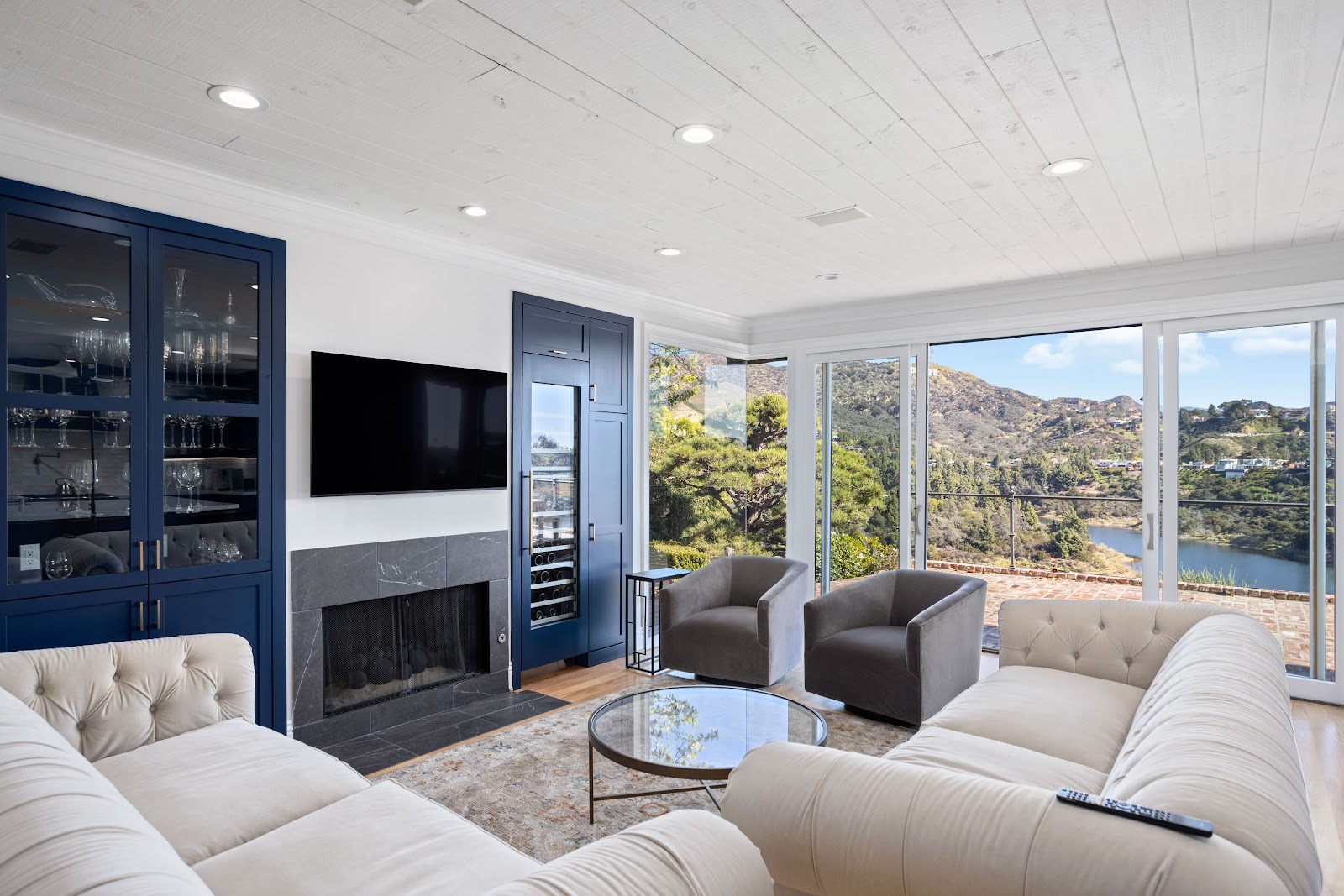 Living room with glass fronted wine storage and full height view windows