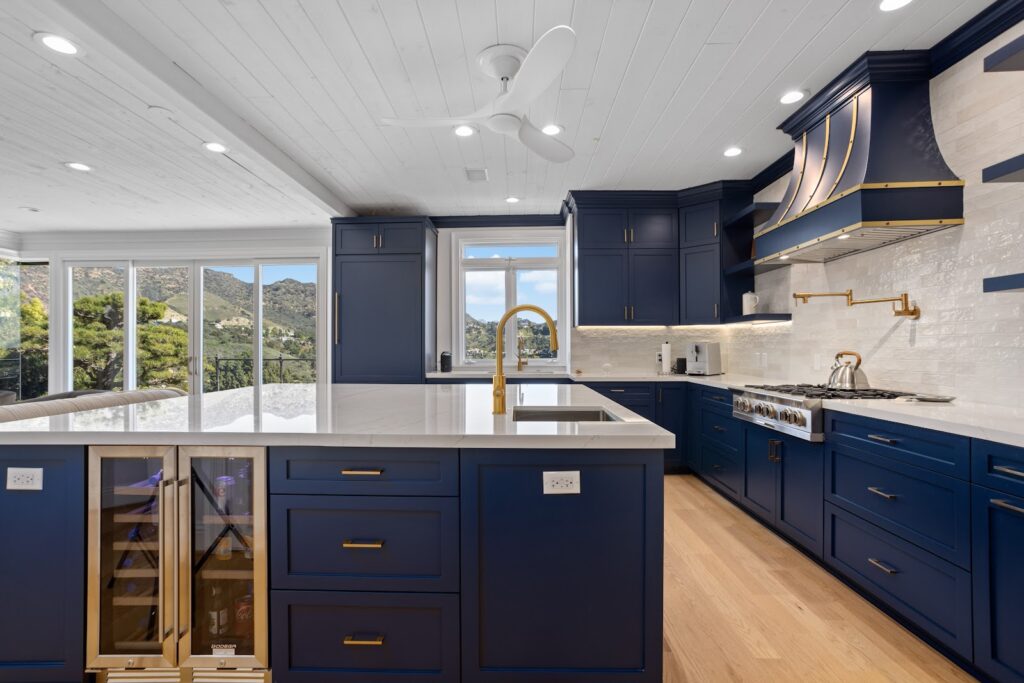 Luxury kitchen remodeling with navy cabinets, a brass faucet and a hillside view