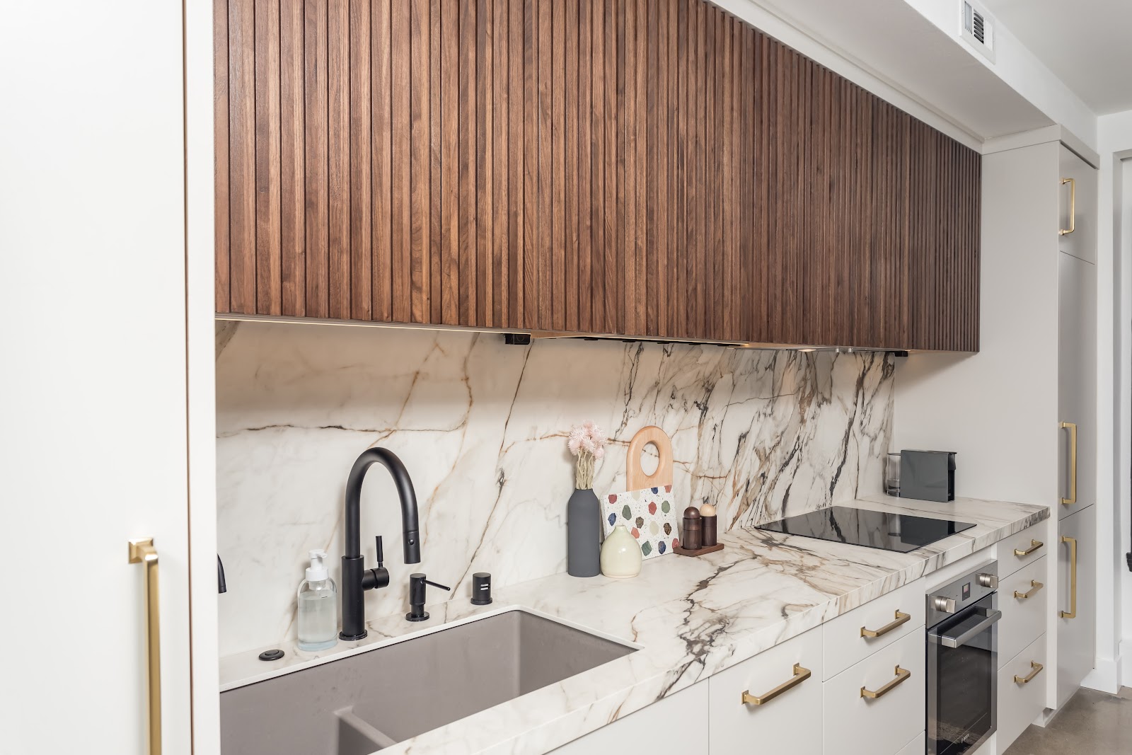 Marble slab backsplash behind a black gooseneck faucet and undermount sink