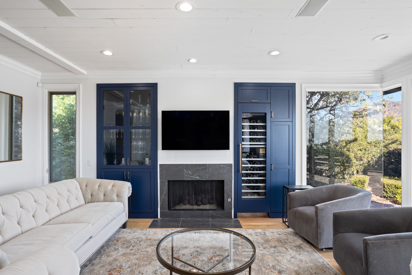 Navy kitchen cabinetry with long brass pulls over light oak flooring