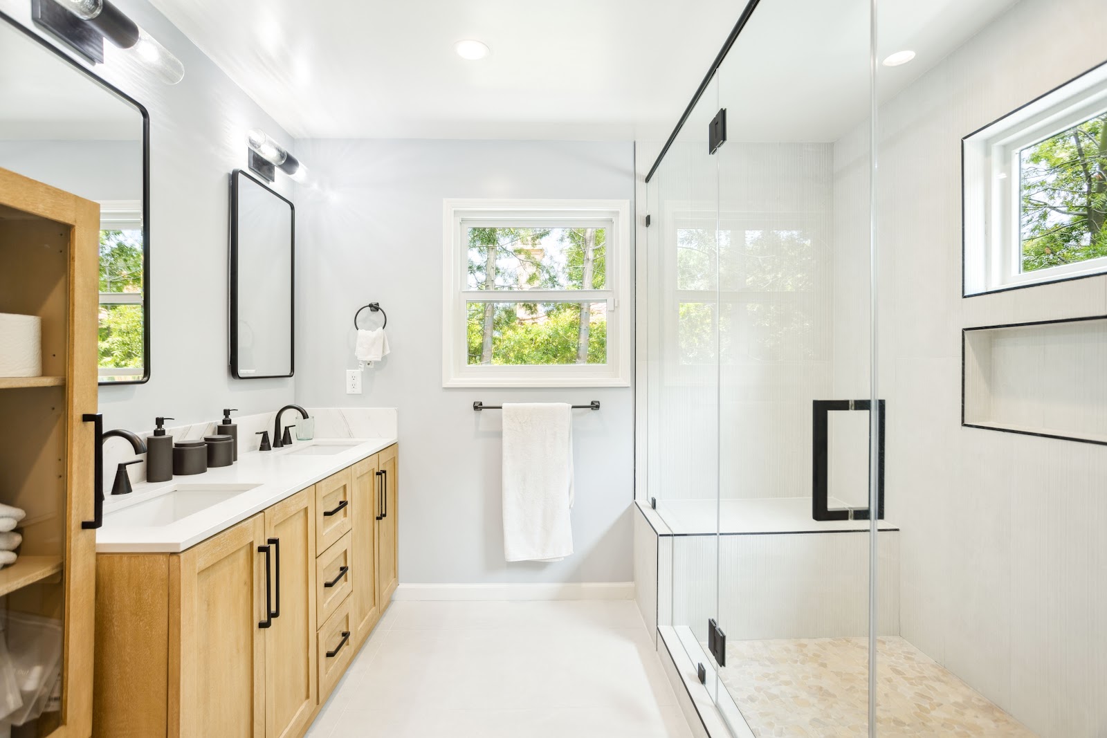 Oak double vanity beside a glass walk in shower in a bathroom remodel