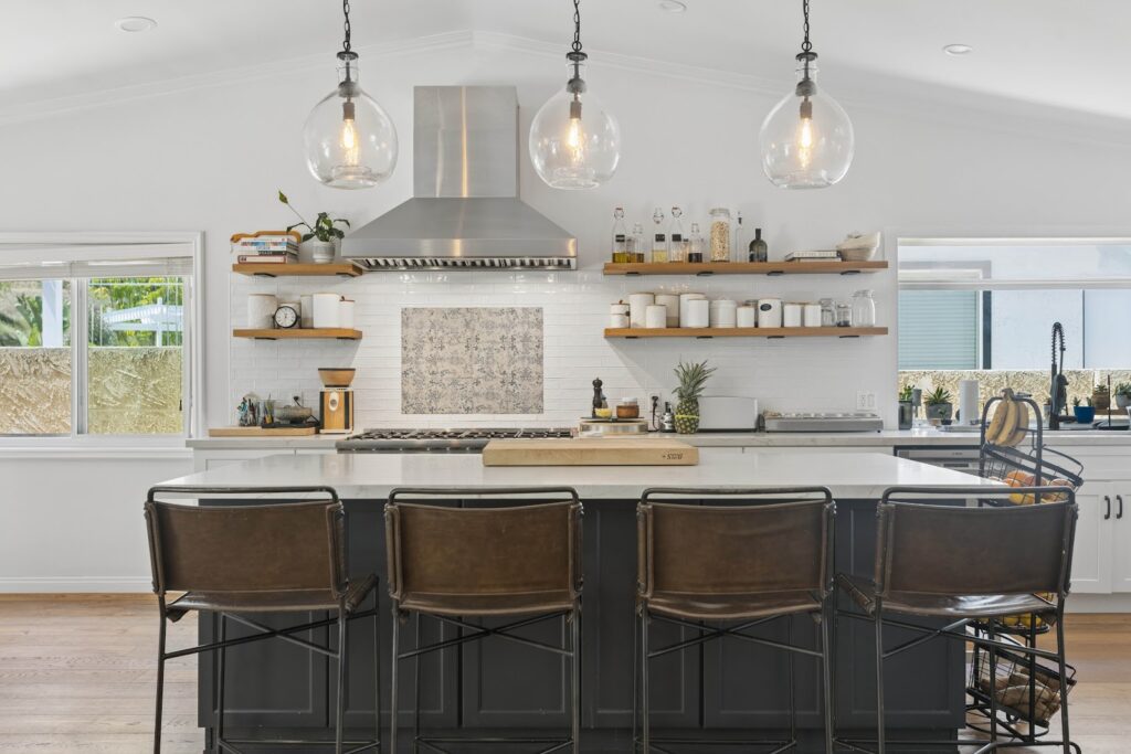Open concept kitchen with a charcoal island and leather stools under a vaulted ceiling