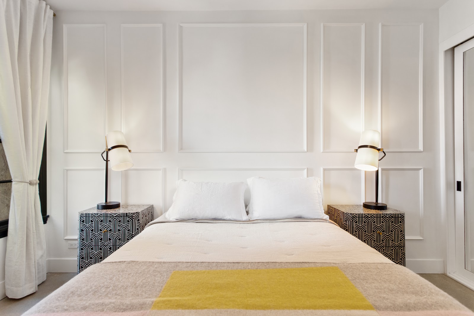 Panelled bedroom wall with matching bedside lamps, one of several home remodeling ideas