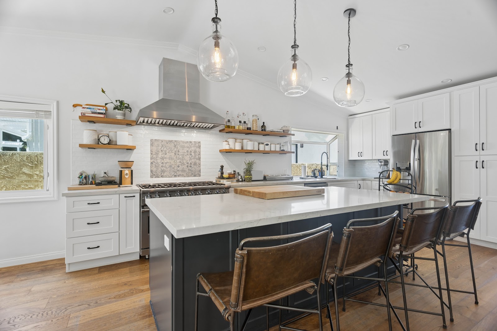 Professional range and stainless hood against a patterned tile panel