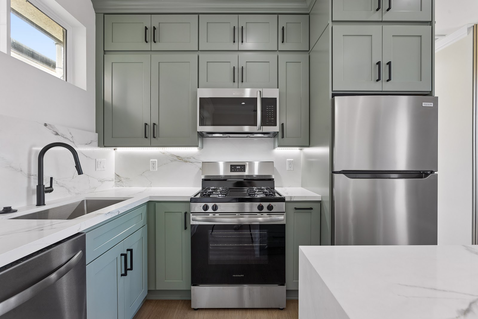 Sage green ADU kitchen with a full height quartz backsplash