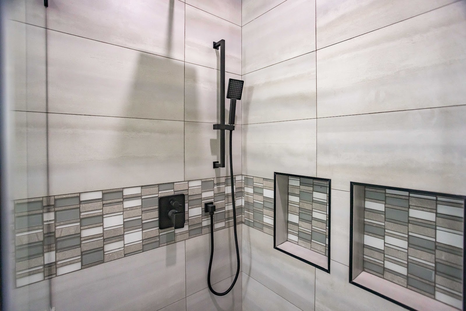 Shower niches and black fixtures set into large format tile