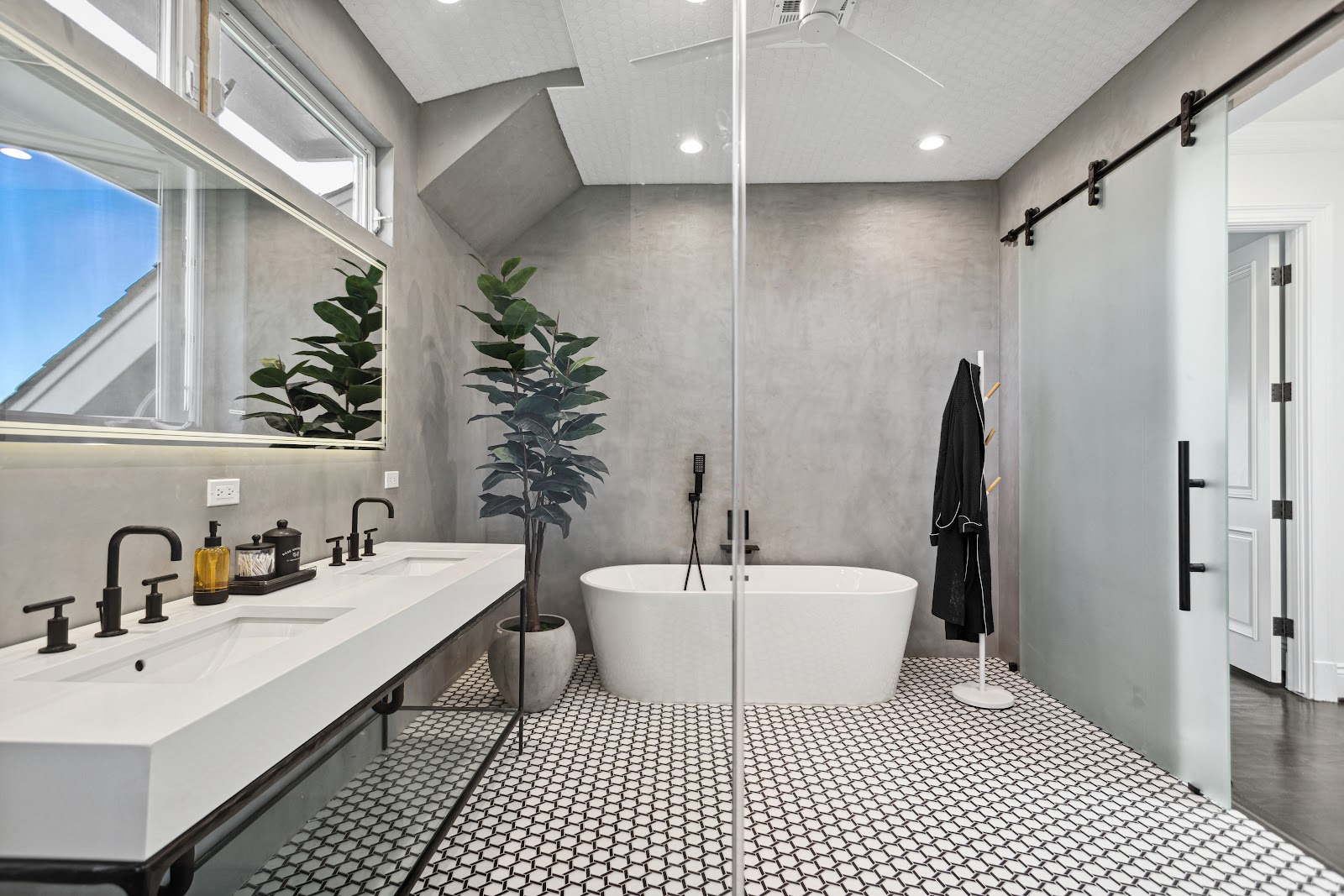 Spa bathroom with a black barn door beside a freestanding tub