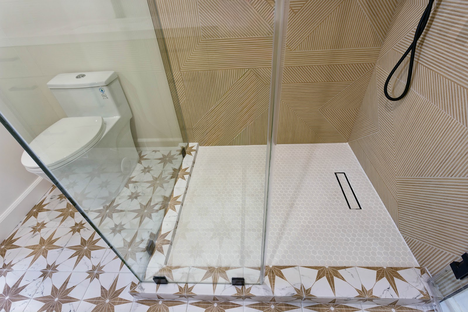 Walk in shower with a linear drain and mosaic floor, level with the room