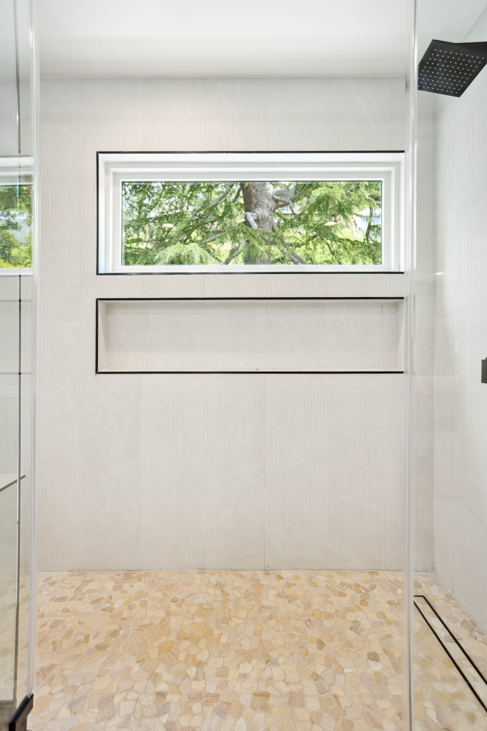 Walk in shower with a pebble stone floor, bench and recessed niche