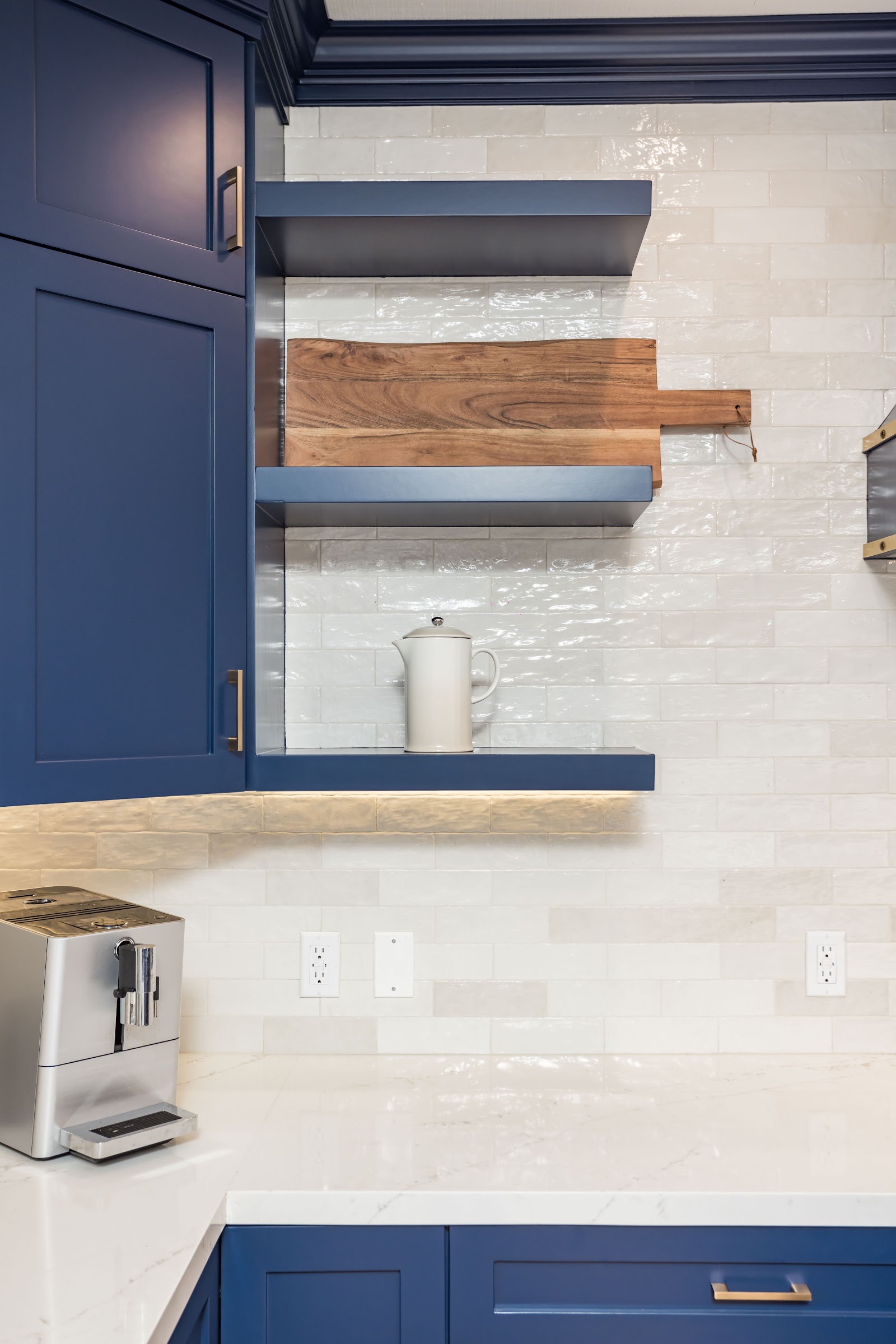 Walnut floating shelves mounted against a stone backsplash